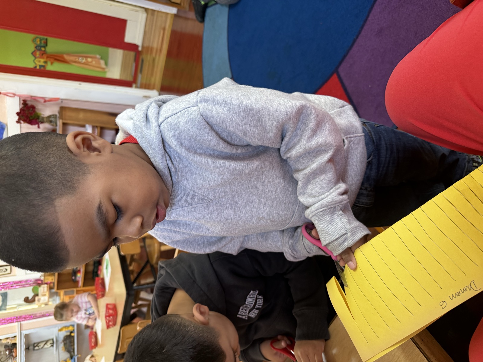 A boy concentrating as he practices cutting along lines with scissors